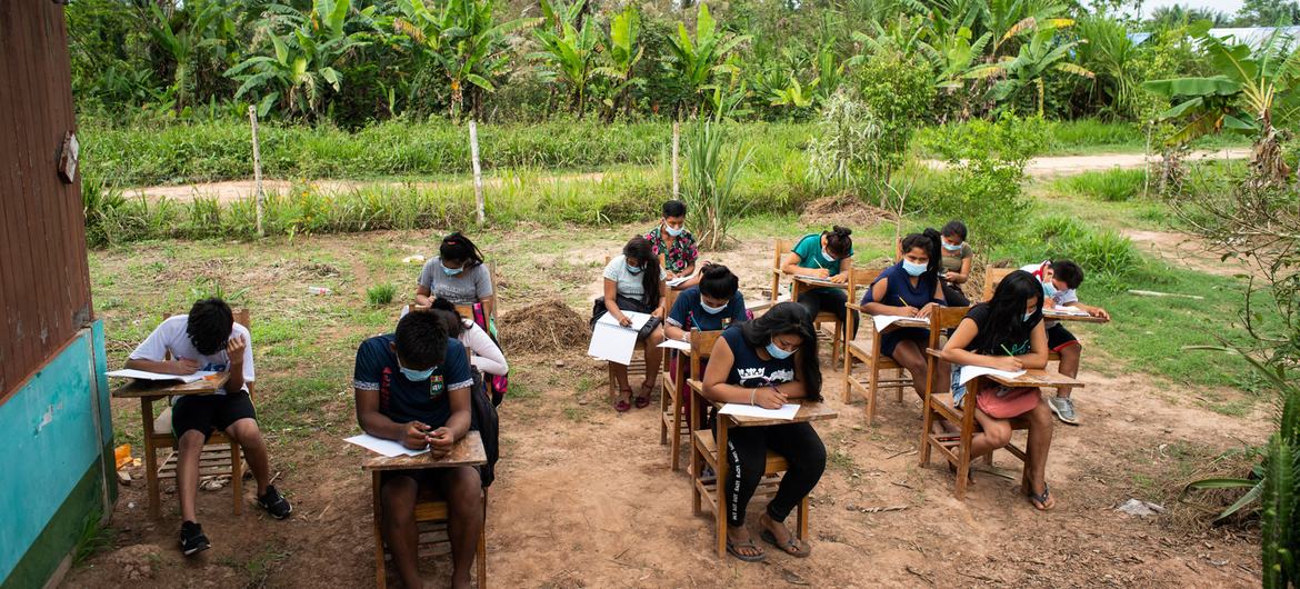 دانش آموزان خارج از مدرسه E Alfonso Ugarte در جامعه San Rafael Shipibo در منطقه Masisea در پرو به دلیل تعلیق کلاس ها در طول همه گیری COVID-19 می نشینند.