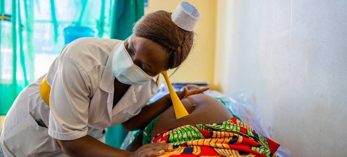 یک پرستار یک مادر باردار را در حین بازدید از مراقبت های دوران بارداری در یک مرکز بهداشتی در اوگاندا معاینه می کند.