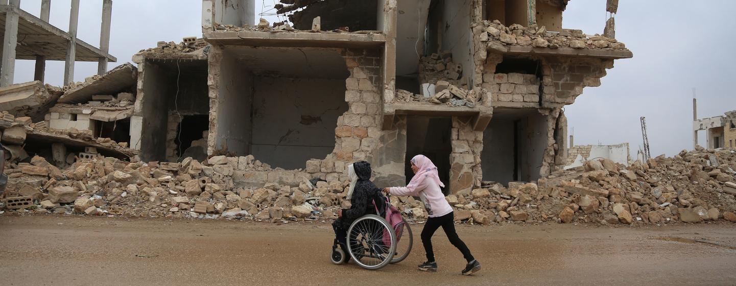 دختری در راه بازگشت از مدرسه به خانه در ادلب سوریه به خواهرش کمک می کند.
