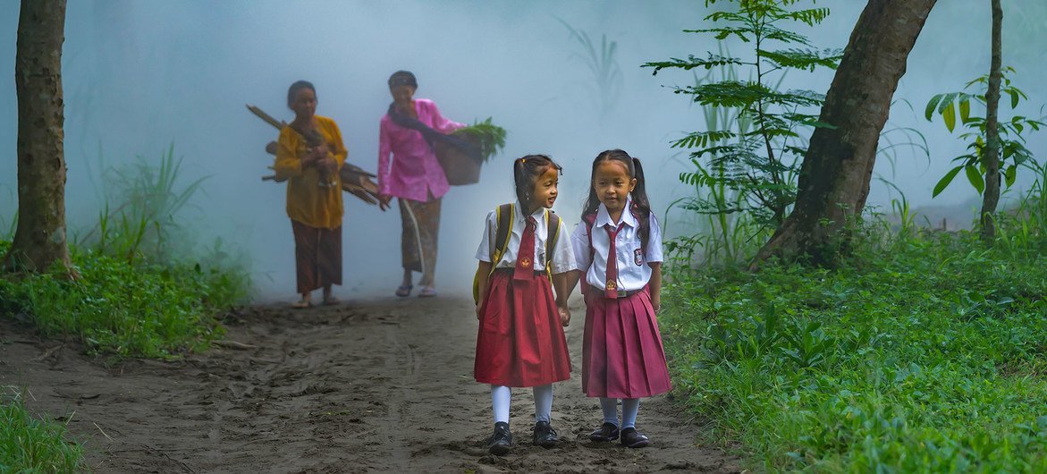 دو دختر دانش آموز جوان در جنگلی در اندونزی قدم می زنند.
